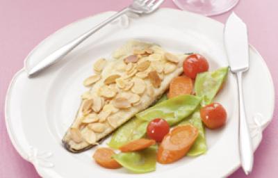 Fotografia em tons de rosa em uma mesa de madeira rosa com um prato branco raso e um filé de truta com amêndoas laminadas e salada dentro dele. Fotografia em tons de rosa em uma mesa de madeira rosa com um prato branco raso e um filé de truta com amêndoas laminadas e salada dentro dele.