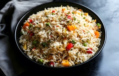 Prato de porcelana com porção de arroz com pimentões vermelhos e amarelos cortados em cubos, cenouras em cubos e ervilhas. Decorado com cheiro-verde picado. Prato de porcelana com porção de arroz com pimentões vermelhos e amarelos cortados em cubos, cenouras em cubos e ervilhas. Decorado com cheiro-verde picado.