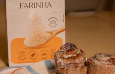 Fotografia em tons de amarelo em uma bancada com um prato azul ao centro e três cinnamon rolls em cima. Ao fundo, uma embalagem de nestlé farinha de aveia.