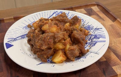 imagem mostra um prato com um guisado com pedaços de carne, cenoura e batatas