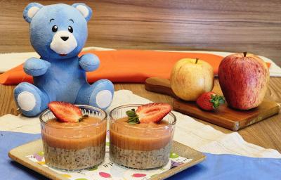 Fotografia de dois copos pequenos de vidro com pudim de pera com morango, e por cima de cada um, tem uma metade de morango para decorar. Os recipientes estão sobre um apoio quadrado. Ao fundo, tem o urso azul de mucilon e as frutas usadas na receita. Fotografia de dois copos pequenos de vidro com pudim de pera com morango, e por cima de cada um, tem uma metade de morango para decorar. Os recipientes estão sobre um apoio quadrado. Ao fundo, tem o urso azul de mucilon e as frutas usadas na receita.