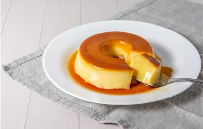 Foto de pudim disposto em um prato branco cortado com uma colher
