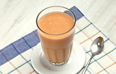 acima de um pano listrado nas cores azul e branco, contém um pratinho com o copo da vitamina e ao lado uma colher. acima de um pano listrado nas cores azul e branco, contém um pratinho com o copo da vitamina e ao lado uma colher.