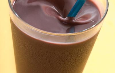 Fotografia em tons de amarelo em uma mesa de madeira amarela, com um copo de vidro alto com a vitamina de açaí dentro dele. Fotografia em tons de amarelo em uma mesa de madeira amarela, com um copo de vidro alto com a vitamina de açaí dentro dele.