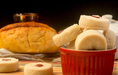 Fotografia de biscoitinhos amanteigados recheados com docinho de Leite MOÇA e NESQUIK de morango dentro de um recipiente de vidro branco e vermelho. Ao lado tem dois biscoitinhos jogados e no fundo tem um pão. Fotografia de biscoitinhos amanteigados recheados com docinho de Leite MOÇA e NESQUIK de morango dentro de um recipiente de vidro branco e vermelho. Ao lado tem dois biscoitinhos jogados e no fundo tem um pão.