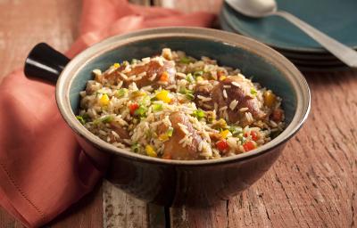 Fotografia em tons de marrom, contém um recipiente redondo com arroz e pedaços de frango Fotografia em tons de marrom, contém um recipiente redondo com arroz e pedaços de frango
