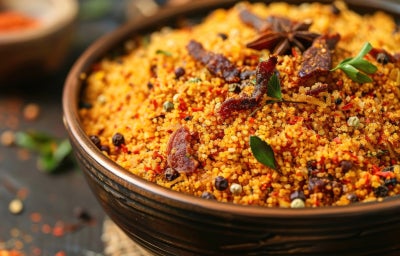 imagem mostra uma travessa com uma farofa com bastante carne seca desfiada e folhas de coentro