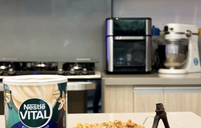 Fotografia em tons de verde e azul em uma bancada de cozinha com um prato vermelho e uma banana assada em cima dele.