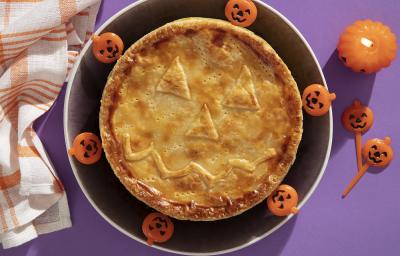 Foto da receita de Torta Folhada Cremosa de Frango com Abóbora para o Dia das Bruxas servida em um prato grande preto com decoração de halloween em volta Foto da receita de Torta Folhada Cremosa de Frango com Abóbora para o Dia das Bruxas servida em um prato grande preto com decoração de halloween em volta