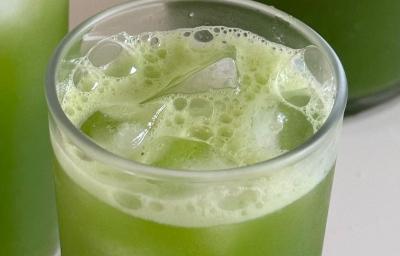 Fotografia de três copos de vidro com suco verde e fiber mais de limão. Os copos estão sobre uma mesa branca, e dentro deles, com o suco, tem cubos de gelo. Fotografia de três copos de vidro com suco verde e fiber mais de limão. Os copos estão sobre uma mesa branca, e dentro deles, com o suco, tem cubos de gelo.