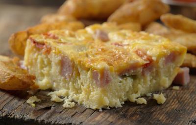 Fotografia de uma torta de panqueca recheada cortada em pedaços, sobre uma tábua de madeira.