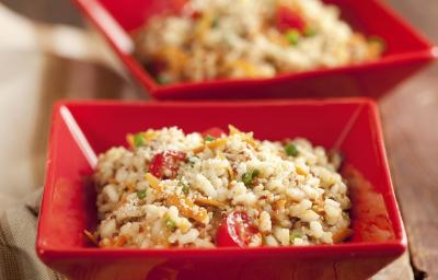 Fotografia em tons de vermelho, marrom e branco, com dois potinhos quadrados contendo um arroz colorido e queijo ralado, ao lado guardanapo em tons de branco e marrom, tudo sobre bancada de madeira rústica. Fotografia em tons de vermelho, marrom e branco, com dois potinhos quadrados contendo um arroz colorido e queijo ralado, ao lado guardanapo em tons de branco e marrom, tudo sobre bancada de madeira rústica.