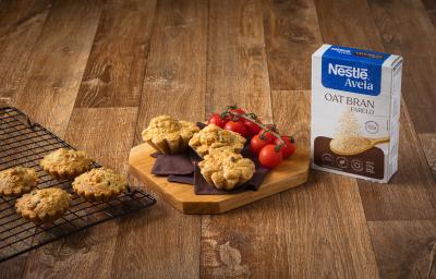 Foto da receita de tortinha de legumes com Nestlé Aveia disposta em 3 porções sobre uma tábua de madeira com tomates-cereja e a embalagem de aveia ao lado