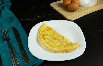 Fotografia em tons mais escuros de um prato branco com uma crepioca dobrada na metade. O prato está sobre uma mesa preta e ao lado de talheres, os quais estão apoiados em um pano de tom azul. Fotografia em tons mais escuros de um prato branco com uma crepioca dobrada na metade. O prato está sobre uma mesa preta e ao lado de talheres, os quais estão apoiados em um pano de tom azul.