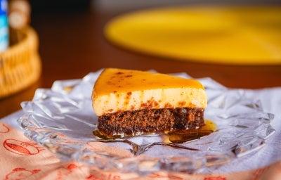 Fotografia mostra uma fatia do bolo pudim, onde são visíveis as camadas de bolo de chocolate e pudim. Fotografia mostra uma fatia do bolo pudim, onde são visíveis as camadas de bolo de chocolate e pudim.