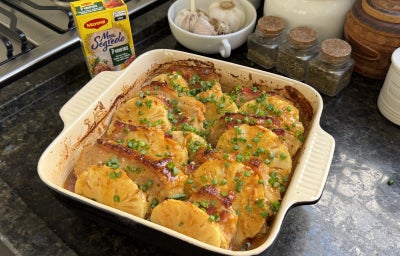 Fotografia mostra uma travessa com lombo e abacaxi intercalados, sobre uma bancada preta.