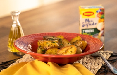 Foto da Receita de Batata Bolinha Sautée. Observa-se um prato vermelho com as batatinhas. Do lado esquerdo, um pote transparente com azeite e, do direito, um garfo e uma embalagem de Maggi Meu Segredo 7 Vegetais. Foto da Receita de Batata Bolinha Sautée. Observa-se um prato vermelho com as batatinhas. Do lado esquerdo, um pote transparente com azeite e, do direito, um garfo e uma embalagem de Maggi Meu Segredo 7 Vegetais.