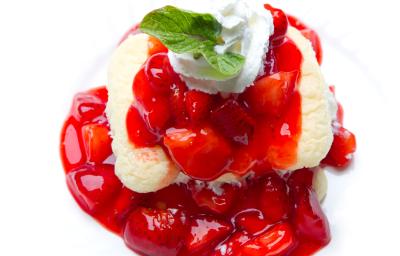 Fotografia em tons claros de uma receita de cremoso de baunilha com frutas vermelhas sobre um apoio branco.