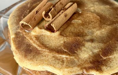 Fotografia mostra um bolo com cobertura de creme claro, polvilhado com canela.