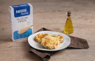 Foto da receita de pizza de abobrinha com aveia servida em 3 porções em um prato branco sobre um pano marrom escuro em cima de uma mesa de madeira com um dispenser de azeite feito de vidro ao lado direito Foto da receita de pizza de abobrinha com aveia servida em 3 porções em um prato branco sobre um pano marrom escuro em cima de uma mesa de madeira com um dispenser de azeite feito de vidro ao lado direito