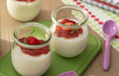 Fotografia de três recipientes de vidro pequenos com pudim de tapioca de ninho um creme de morango por cima. Dois desses recipientes estão sobre um apoio verde retangular, ao lado de uma colher roxa pequena. Fotografia de três recipientes de vidro pequenos com pudim de tapioca de ninho um creme de morango por cima. Dois desses recipientes estão sobre um apoio verde retangular, ao lado de uma colher roxa pequena.