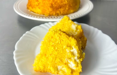 Fotografia em tons claros com um bolo feito com flocão ao centro. O bolo tem cor amarelada e é recheado com requeijao NESTLÉ Cremoso