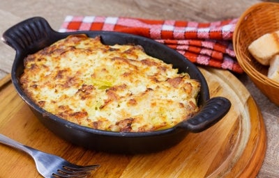 Em cima de uma mesa, refratário preto com queijo gratinado. Em cima de uma mesa, refratário preto com queijo gratinado.
