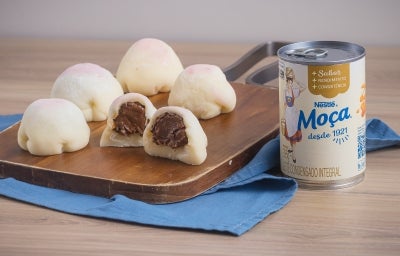 Receita de Mochi de Brigadeiro, servida em pequenas bolinhas brancas, recheadas com brigadeiro enrolado, sobre uma tábua de madeira e um tecido na cor azul ao lado de uma Lata de Leite Moça Receita de Mochi de Brigadeiro, servida em pequenas bolinhas brancas, recheadas com brigadeiro enrolado, sobre uma tábua de madeira e um tecido na cor azul ao lado de uma Lata de Leite Moça