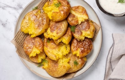 Em cima de uma mesa, prato redondo com batatas ao murro douradas e crocantes. Em cima de uma mesa, prato redondo com batatas ao murro douradas e crocantes.