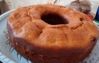 Fotografia de um bolo inteiro de fubá e goiabada sobre um apoio de plástico branco e raso. Fotografia de um bolo inteiro de fubá e goiabada sobre um apoio de plástico branco e raso.