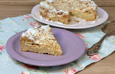 Fotografia em tons de lilás com um prato lilás ao centro. Em cima do prato existe uma receita de bolo de cor caramelo feito com farinha de amêndoas torradas. Fotografia em tons de lilás com um prato lilás ao centro. Em cima do prato existe uma receita de bolo de cor caramelo feito com farinha de amêndoas torradas.