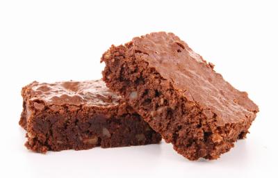Fotografia de dois pedaços de brownie, um apoiado sobre o outro num fundo totalmente branco.
