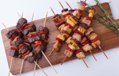 Foto tirada de uma tábua de madeira marrom que contém diversos espetinhos com pedaços de carne Foto tirada de uma tábua de madeira marrom que contém diversos espetinhos com pedaços de carne