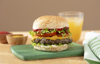 Foto da receita de Hambúrguer de Cogumelo. Observa-se um lanche montado com pão de hambúrguer com gergelim, mostarda, ketchup, alface, tomate e o hambúrguer de cogumelo ao meio.