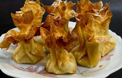 Foto da receita de Trouxinha de Filo com Ovos. Na foto, observa-se 7 trouxinhas assadas em um prato de porcelana branco. Foto da receita de Trouxinha de Filo com Ovos. Na foto, observa-se 7 trouxinhas assadas em um prato de porcelana branco.