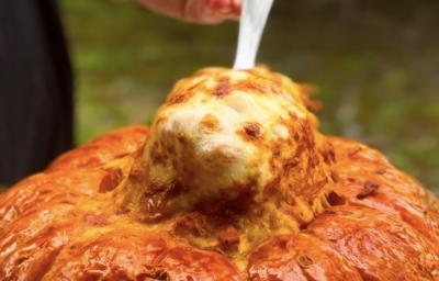 Fotografia de uma colher puxando o strogonoff de camarão com bastante queijo de dentro da abóbora moranga. Fotografia de uma colher puxando o strogonoff de camarão com bastante queijo de dentro da abóbora moranga.
