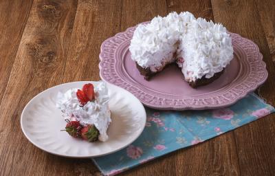 Imagem da receita de Torta Brownie, decorada com chantilly e morangos, servida em um prato rosa e ao lado há um prato menor branco com uma fatia. Tudo está sobre um pano decorado com motivos florais, sobre uma bancada de madeira Imagem da receita de Torta Brownie, decorada com chantilly e morangos, servida em um prato rosa e ao lado há um prato menor branco com uma fatia. Tudo está sobre um pano decorado com motivos florais, sobre uma bancada de madeira