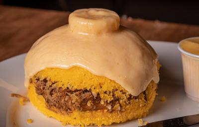 Fotografia de cuscuz de carne seca com fatia de queijo em cima.