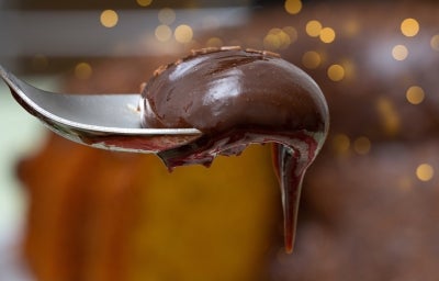 Fotografia de uma colher de sopa segurando um pouco do brigadeiro cremoso de chocolate.