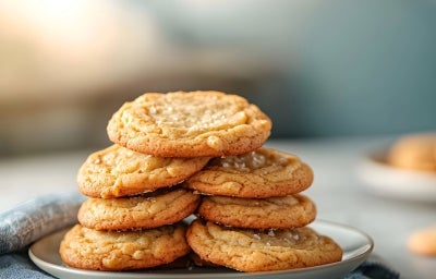 Em cima de uma mesa, prato branco com biscoitos redondos crocantes enfileirado em cima do outro. Em cima de uma mesa, prato branco com biscoitos redondos crocantes enfileirado em cima do outro.