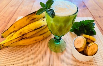 Fotografia em tons de verde e amarelo com um copo de shake ao centro. Em cima do copo, Fotografia em tons de verde e amarelo com um copo de shake ao centro. Em cima do copo,