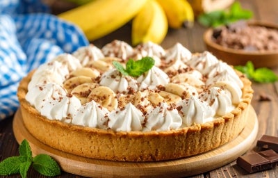 Em cima de uma mesa, banoffe com massa crocante, decorado com chantilly cremoso, bananas cortadas em rodelas e chocolate ralado. Em cima de uma mesa, banoffe com massa crocante, decorado com chantilly cremoso, bananas cortadas em rodelas e chocolate ralado.