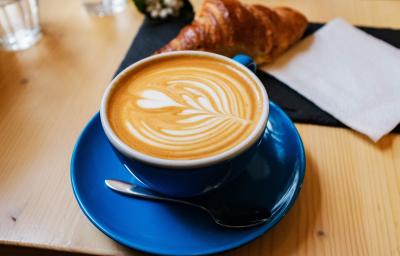 Foto da receita de Flat White. Observa-se uma xícara azul sobre um pires da mesma cor e a bebida dentro, com um formato de coração. Foto da receita de Flat White. Observa-se uma xícara azul sobre um pires da mesma cor e a bebida dentro, com um formato de coração.