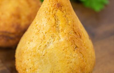Fotografia de uma coxinha de jaca sobre uma tábua de madeira.