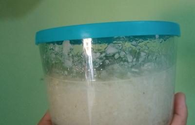 Fotografia de um recipiente de vidro com uma pasta de alho e cebola. O recipiente tem uma tampa azul claro.