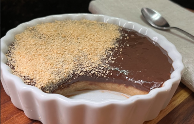 A imagem mostra uma travessa de porcelana branca com um creme dentro, sendo que uma porção do creme ja foi retirada.