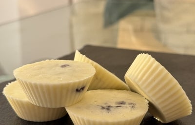 Fotografia em tons claros com uma fotografia de vários bombons brancos ao centro feitos em forminhas de silicone.
