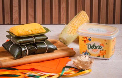 Pamonhas cozidas em folhas de bananeira empilhadas, pamonha aberta cremosa, espiga de milho e margarina Deline