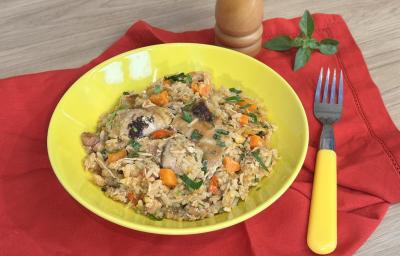 Fotografia em tons de amarelo e vermelho com um prato vermelho ao centro. Dentro do prato existe uma receita de galinhada feita com frango, cenoura e arroz
