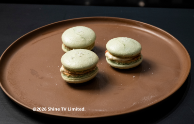 Fotografia em tons escuros com 3 macarons de coentro com pimenta-de-cheiro